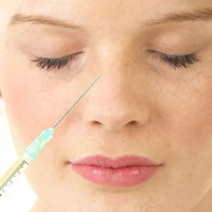 Close-up of a woman with closed eyes, preparing to receive a non-surgical rhinoplasty injection with a syringe aimed at the bridge of her nose.