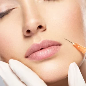 Close-up of a woman receiving a cosmetic lip injection with a syringe, while a professional wearing white gloves gently holds her face during the aesthetic procedure.