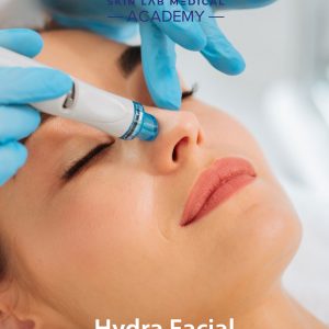 Close-up of a woman receiving a HydraFacial treatment at a clinic, with a gloved practitioner using a specialized device on her nose. The woman is relaxed with eyes closed, showcasing a skincare procedure under the branding of Skin Lab Medical Academy.